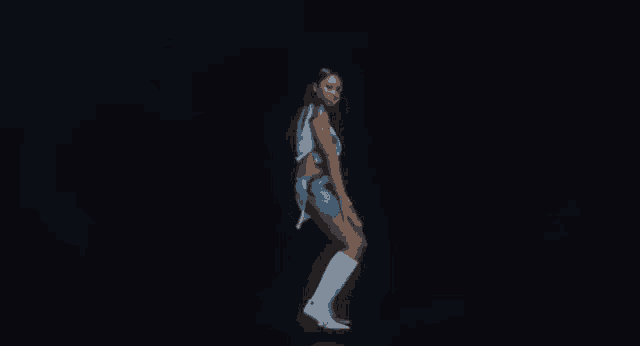 a woman in a blue dress and white boots is dancing on a stage .
