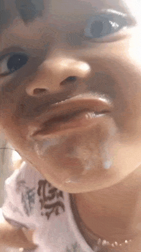 a close up of a child 's face with a white liquid coming out of her mouth