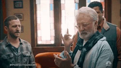 a man with glasses and a beard talks to another man in a perfect harmony advertisement