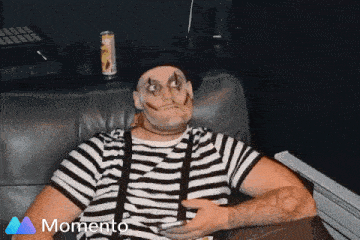 a man in a mime costume is sitting on a couch with a momento logo in the background