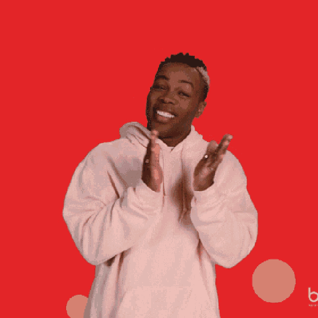 a man in a pink hoodie is clapping his hands in front of a red background that says that 's not it