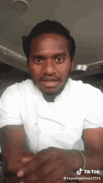 a man with a beard is wearing a white shirt and a green bracelet .