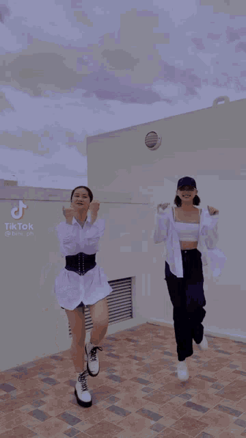 two women are dancing on a tiled floor with tiktok written on the bottom