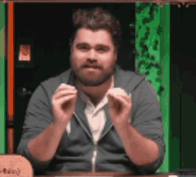 a man with a beard is sitting at a table holding a piece of paper in his hands .