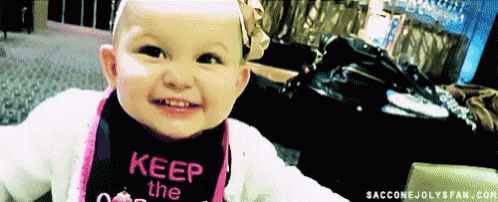 a baby wearing a bib that says keep on smiling at the camera