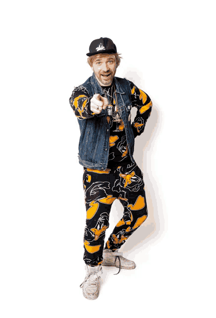 a man wearing a hat and a denim vest is pointing at something