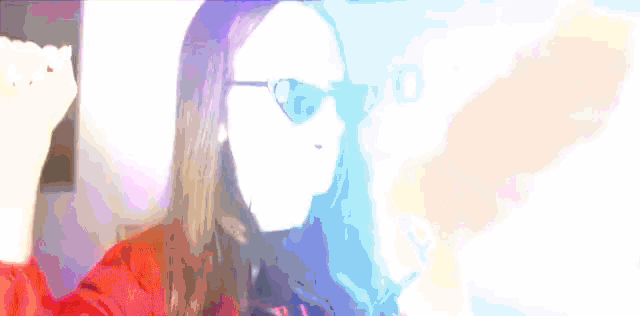 a woman wearing sunglasses and a red jacket is dancing in front of a sign that says love
