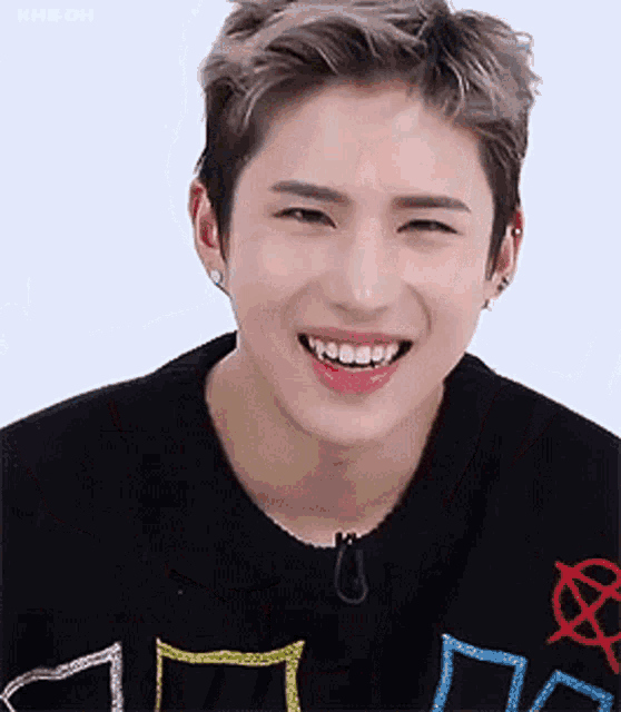 a young man wearing a black sweater is smiling with his teeth showing .