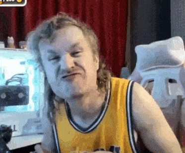 a man with long hair is making a funny face while wearing a yellow tank top .