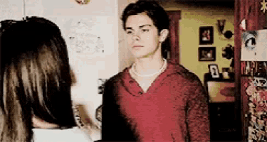 a man in a red shirt is standing next to a woman in a room