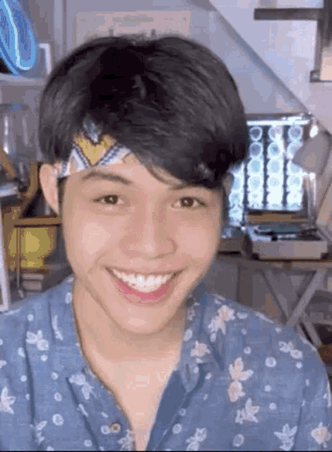 a young man wearing a headband is smiling and wearing a blue shirt .