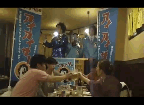 a group of people are toasting in front of a sign that says ' ape ' on it