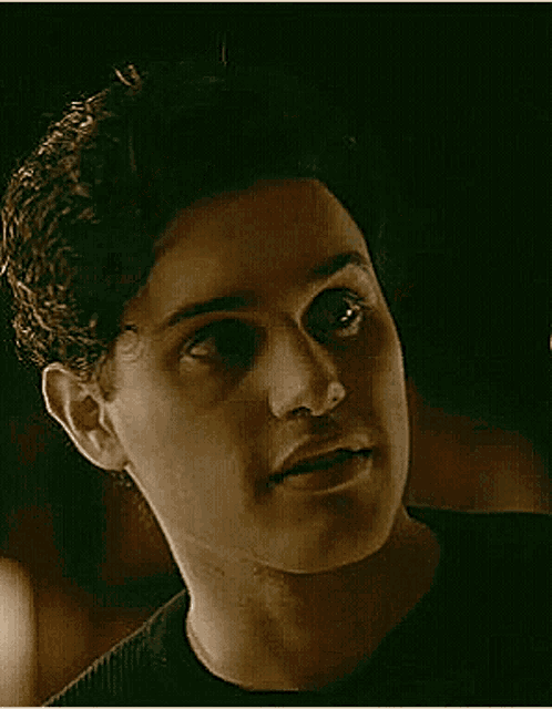 a close up of a young man 's face in a dark room looking at the camera .