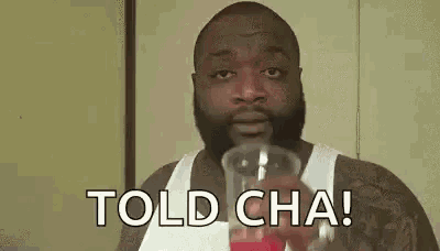 a man with a beard is drinking from a cup and saying `` told cha ! ''