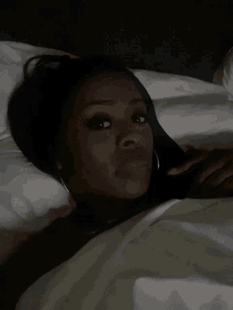 a woman is laying on a bed with a white blanket