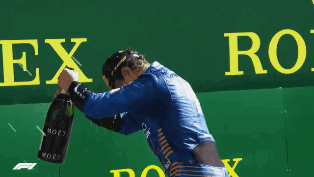 a man is holding a bottle of champagne in front of a rolex logo