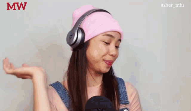 a woman wearing headphones and a pink beanie is making a face .