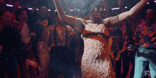 a woman in a dress is dancing in front of a crowd of people .