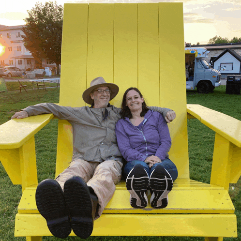 a man and a woman are sitting in a giant yellow chair