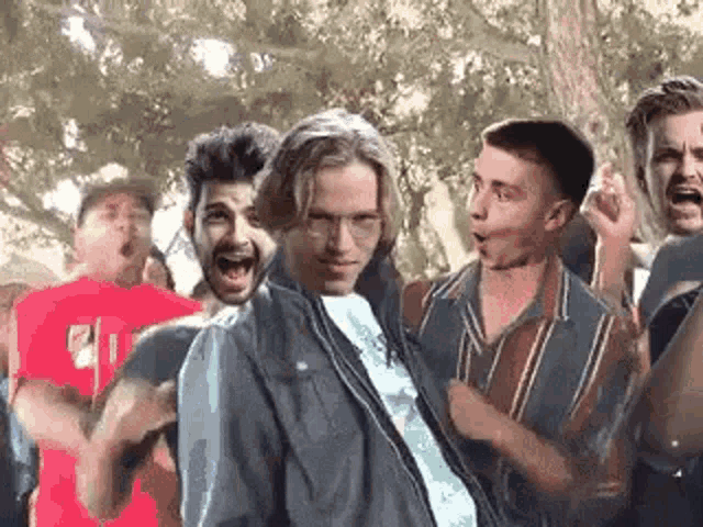 a group of men are standing around a man in a jacket .