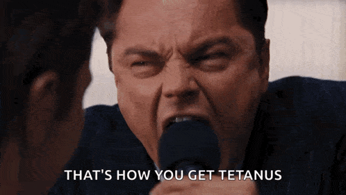 a man in a suit is screaming into a microphone with the words that 's how you get tetanus behind him