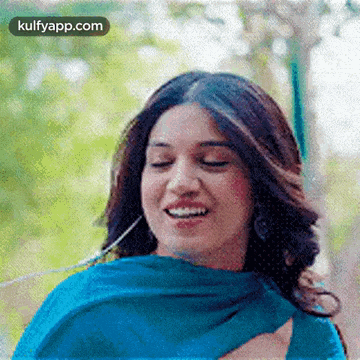 a woman in a blue dress is smiling with her eyes closed and wearing headphones .