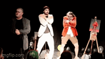 a group of men are dancing on a stage in front of a painting on an easel