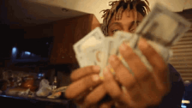 a man is holding a pile of money in his hands .
