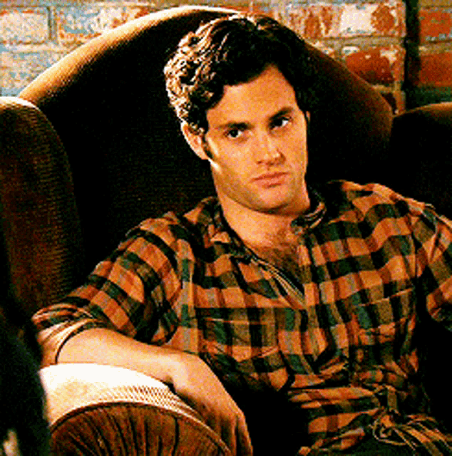 a man in a plaid shirt sitting in a chair