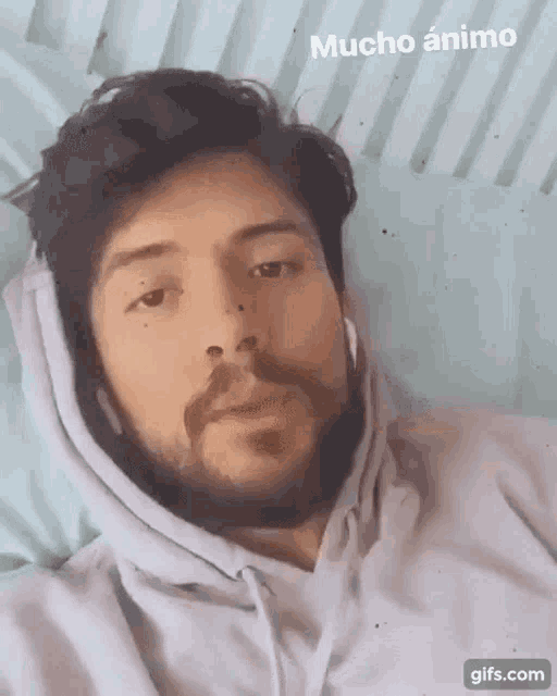 a man with a beard wearing a hoodie and headphones with the words mucho animo written above him