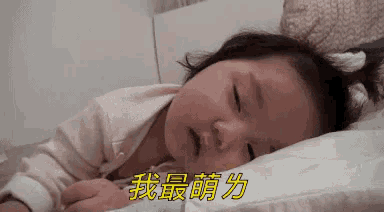 a baby is sleeping on a bed with chinese writing on the bottom