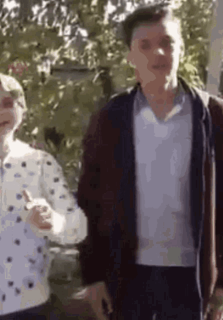 a man and a woman are standing next to each other . the woman is giving a thumbs up .