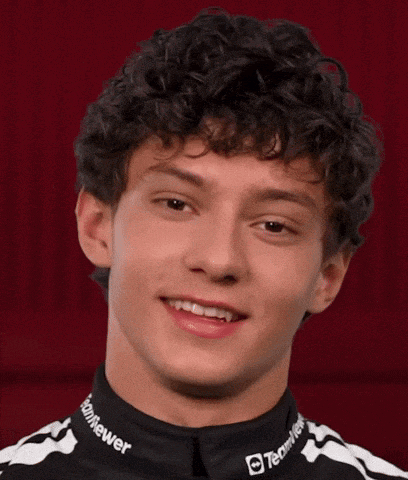 a young man with curly hair is wearing a black and white striped shirt that says good question