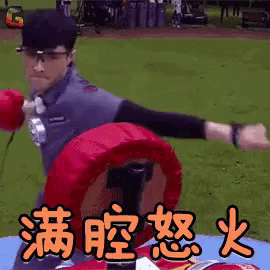a man wearing glasses is holding a boxing glove in front of a sign with chinese writing on it