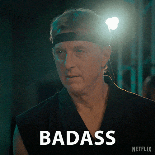 a man wearing a headband stands in front of a sign that says badass on it