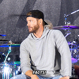 a man sitting in front of a drum set with the words " facts " on his shirt