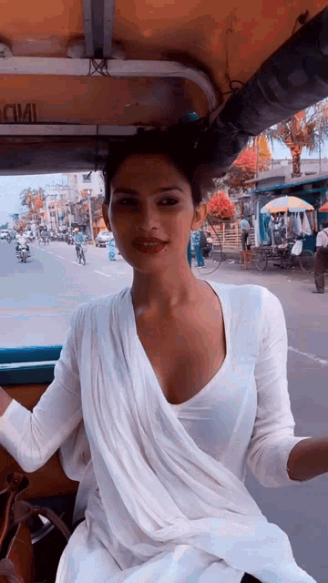 a woman in a white dress is sitting in the back of a taxi .