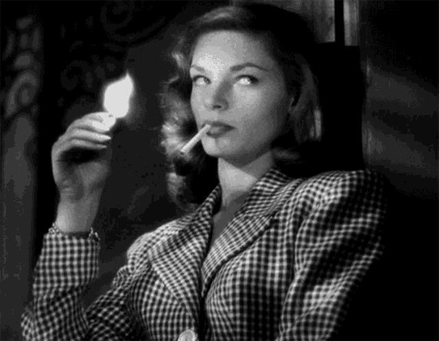 a woman in a plaid jacket lighting a cigarette with a match