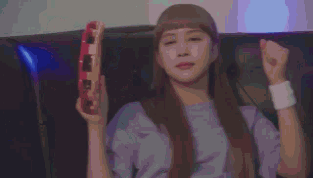 a woman with long hair is sitting on a couch holding a tambourine