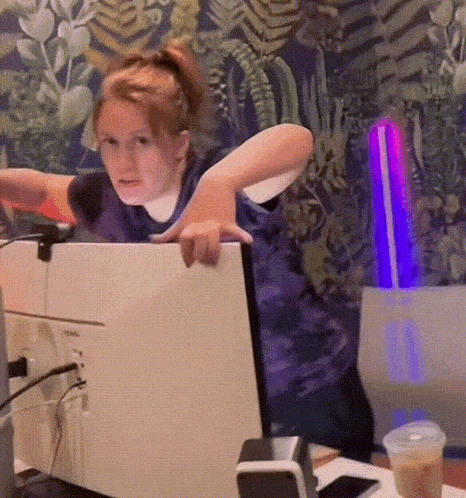 a young girl is standing in front of a computer screen looking at it