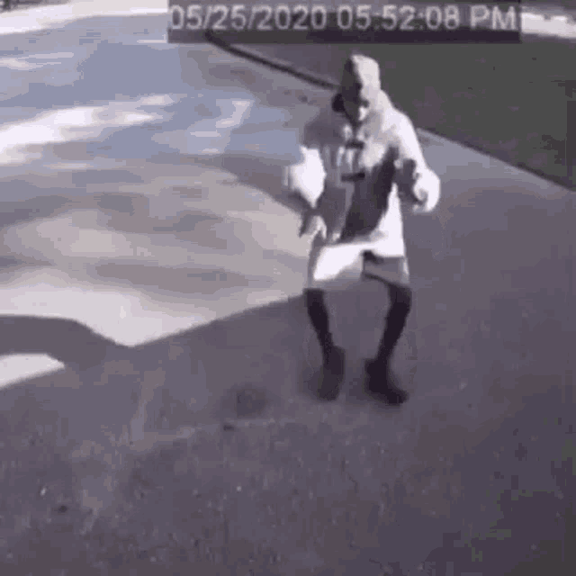 a man is dancing on a sidewalk in front of a camera .