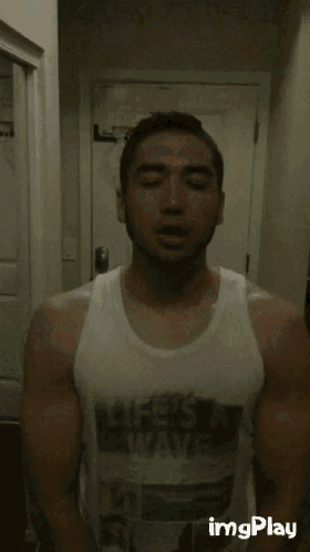 a man wearing a white tank top that says life 's a wave on it