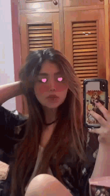 a girl is taking a picture of herself in a mirror with hearts in her eyes .