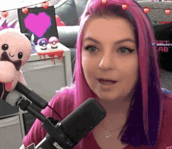 a woman with pink hair is speaking into a microphone