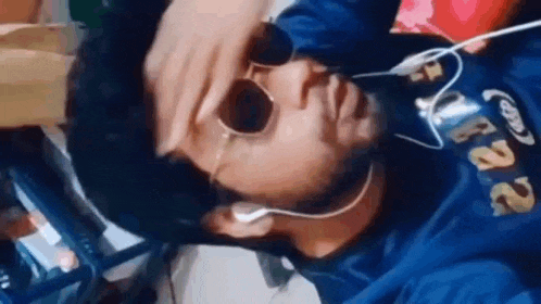 a man wearing headphones and sunglasses is covering his face .
