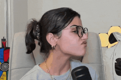 a woman wearing glasses is making a funny face while sitting in front of a microphone