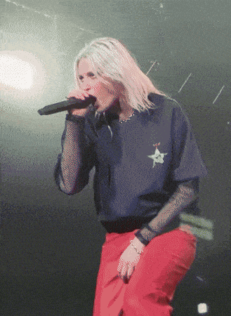a woman singing into a microphone while wearing a shirt with a star on it