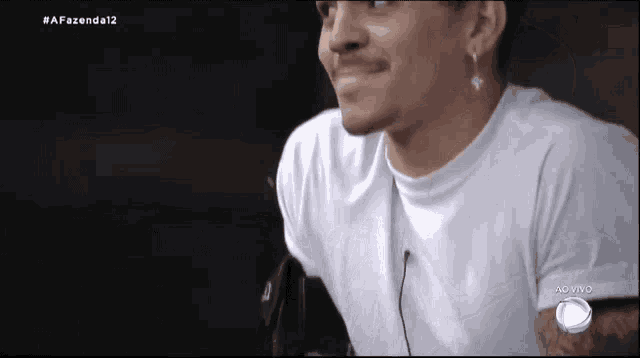 a man wearing a white t-shirt with a cross earring