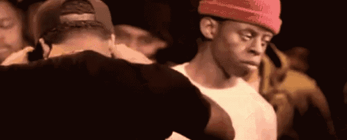 a man wearing a red hat is standing next to another man in a crowd .