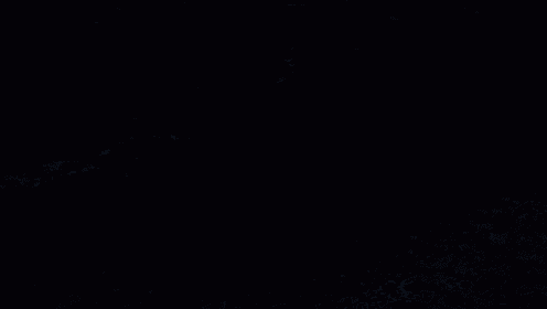 a red car is driving down a road in the dark